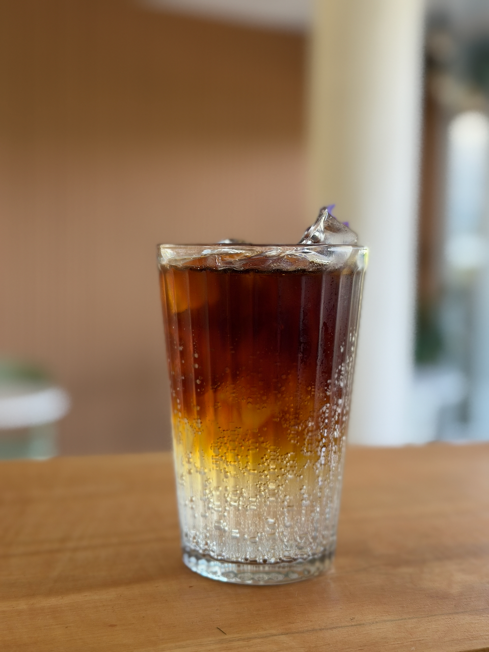 Café frío en vaso alto sobre mesa de madera